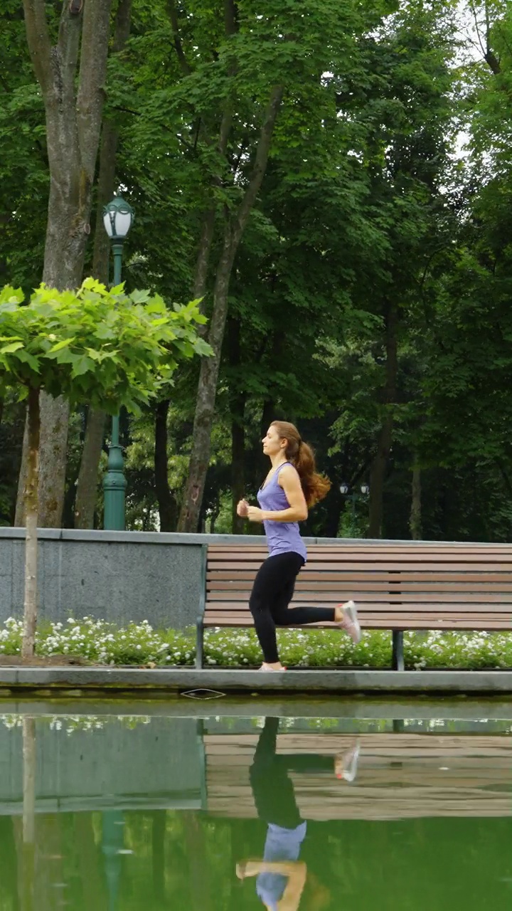 竖屏:在公园池塘边跑步的女人视频素材