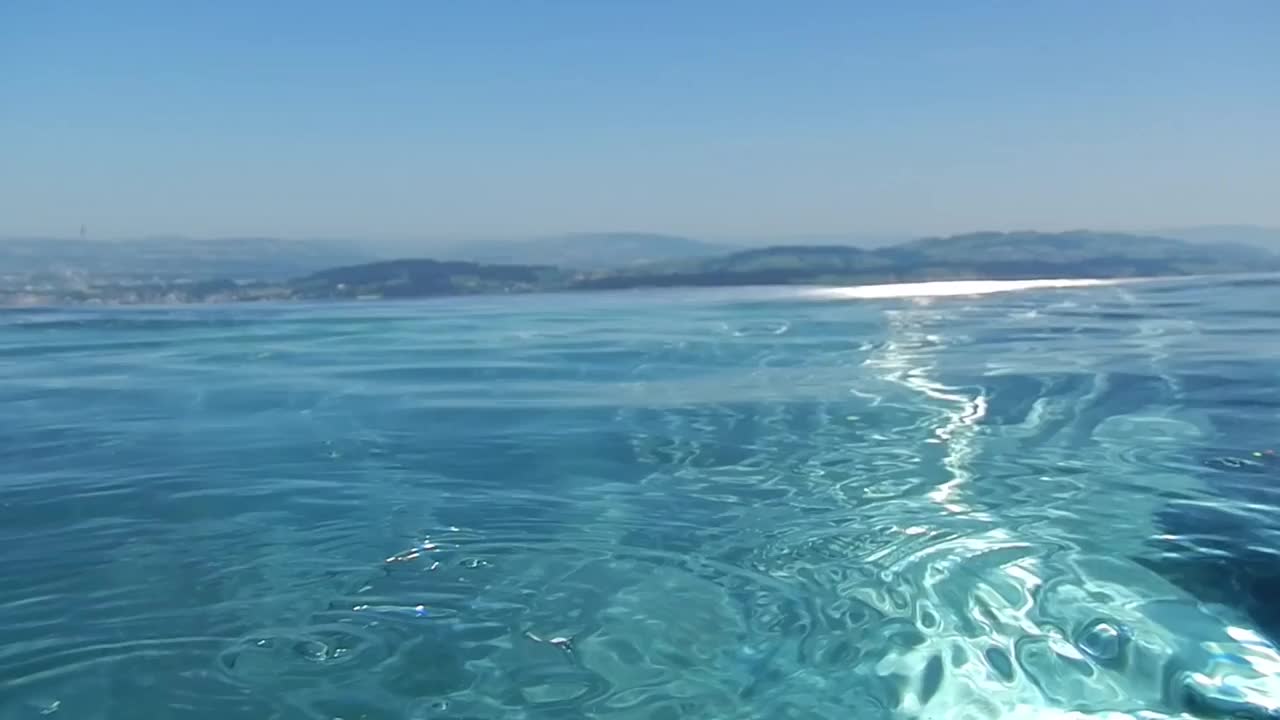 在一个阳光明媚的夏日，在卢塞恩湖和城市，拥有山景和湖景的无限游泳池视频素材