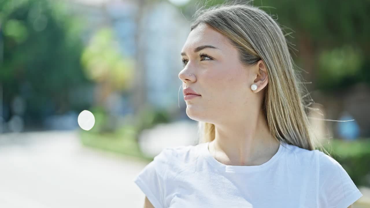 年轻的金发女子站在公园微笑自信视频素材