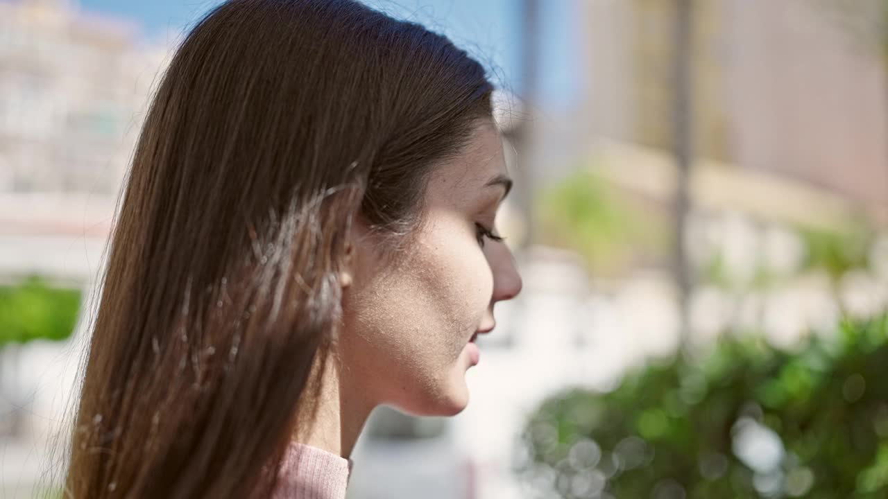 年轻美丽的西班牙女子微笑着自信地在公园用智能手机聊天视频素材