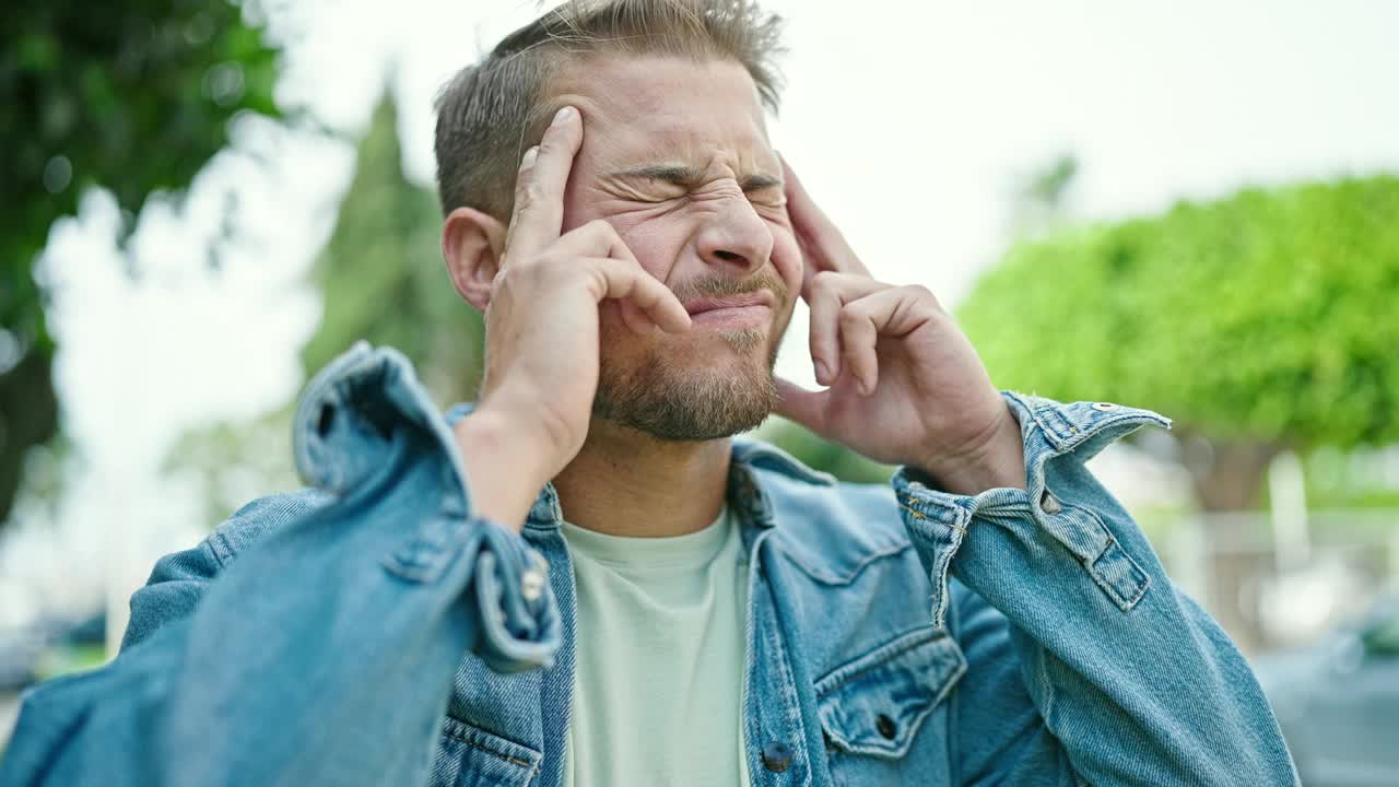 年轻的白人男子在公园患头痛视频素材