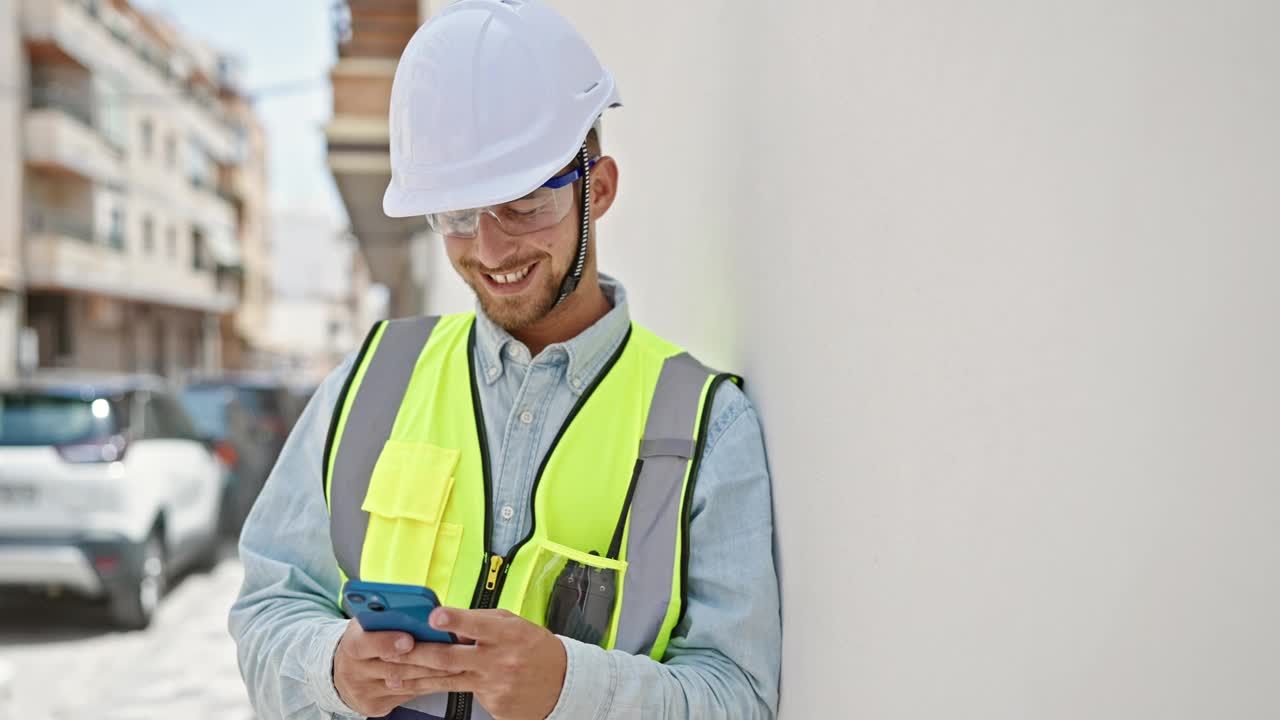 年轻的白人建筑师在工地用智能手机微笑着视频素材