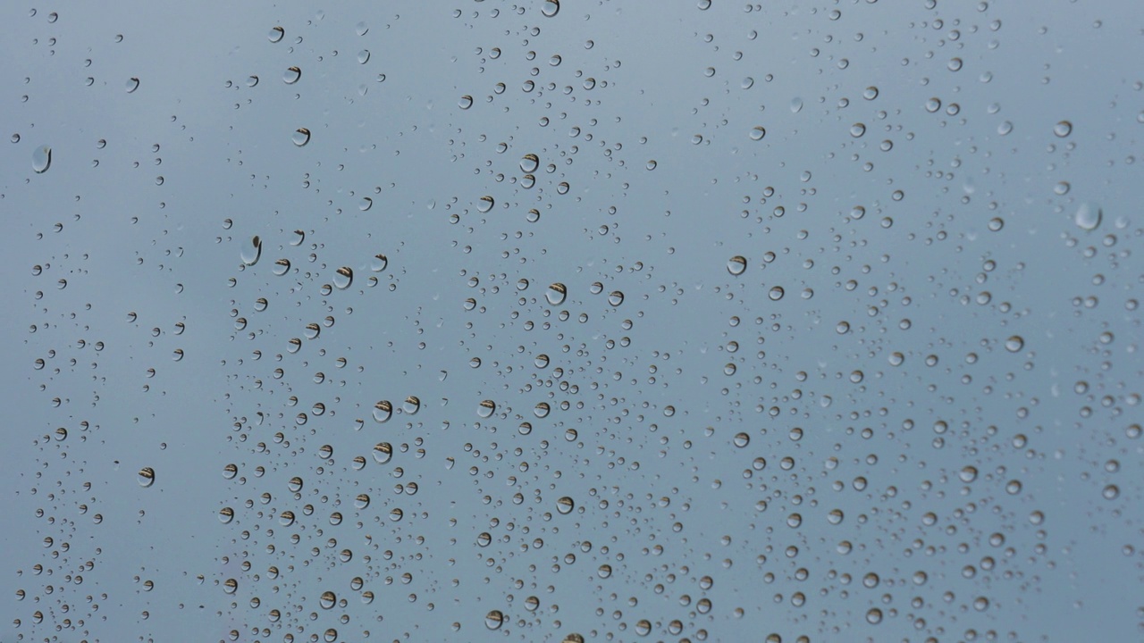 雨点落在天蓝色背景的窗玻璃上视频素材