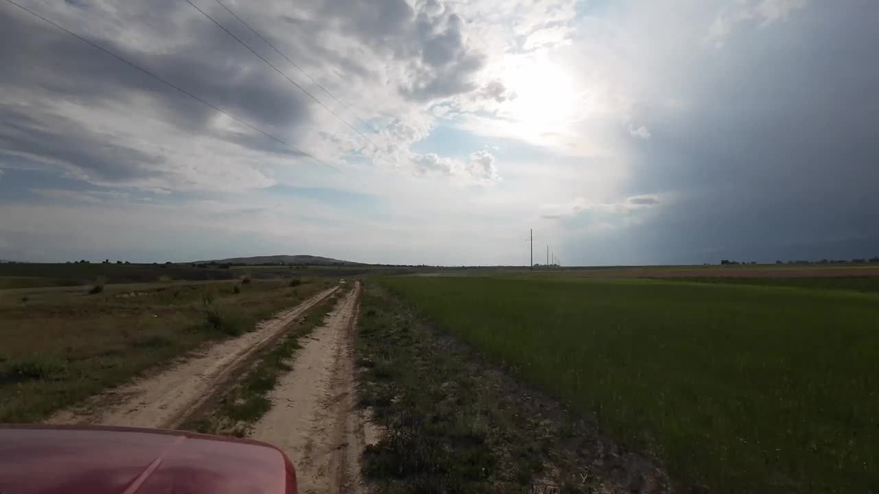 多云天空下田野草地上的路。汽车的观点视频素材