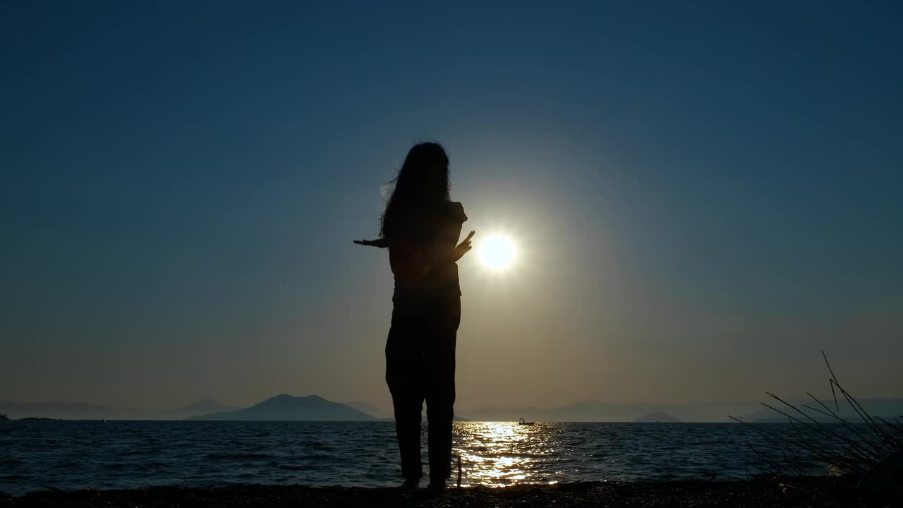 剪影女孩在海湾上跳舞。视频素材