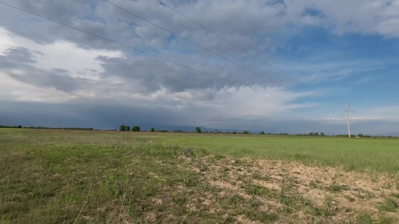 多云天空下田野草地上的路。汽车的观点视频素材