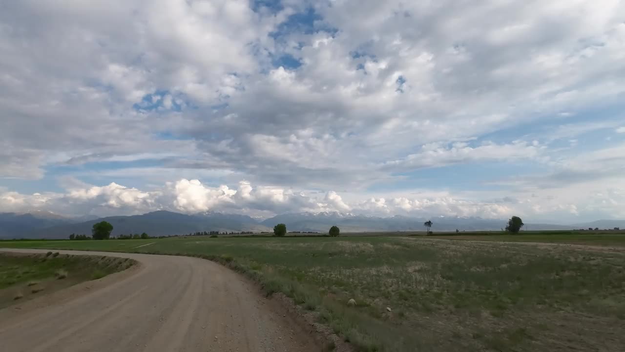 多云天空下田野草地上的路。汽车的观点视频素材