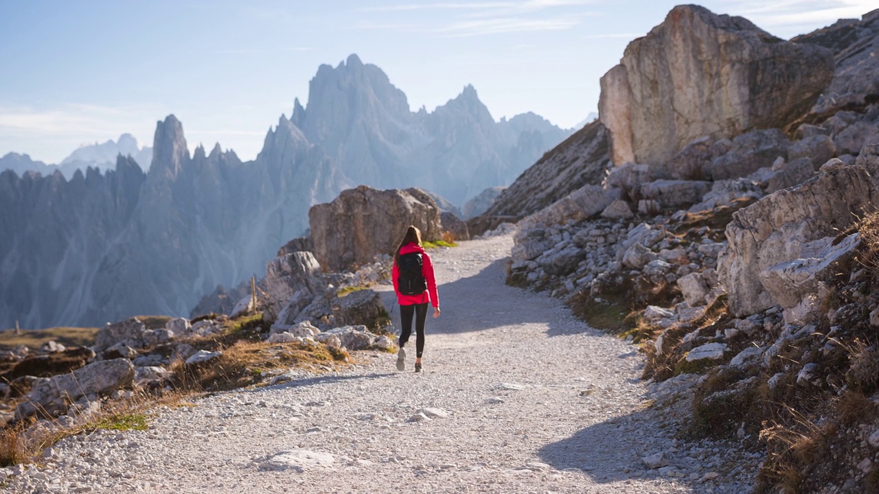 女性徒步旅行的路径与雄伟的山全景视频素材