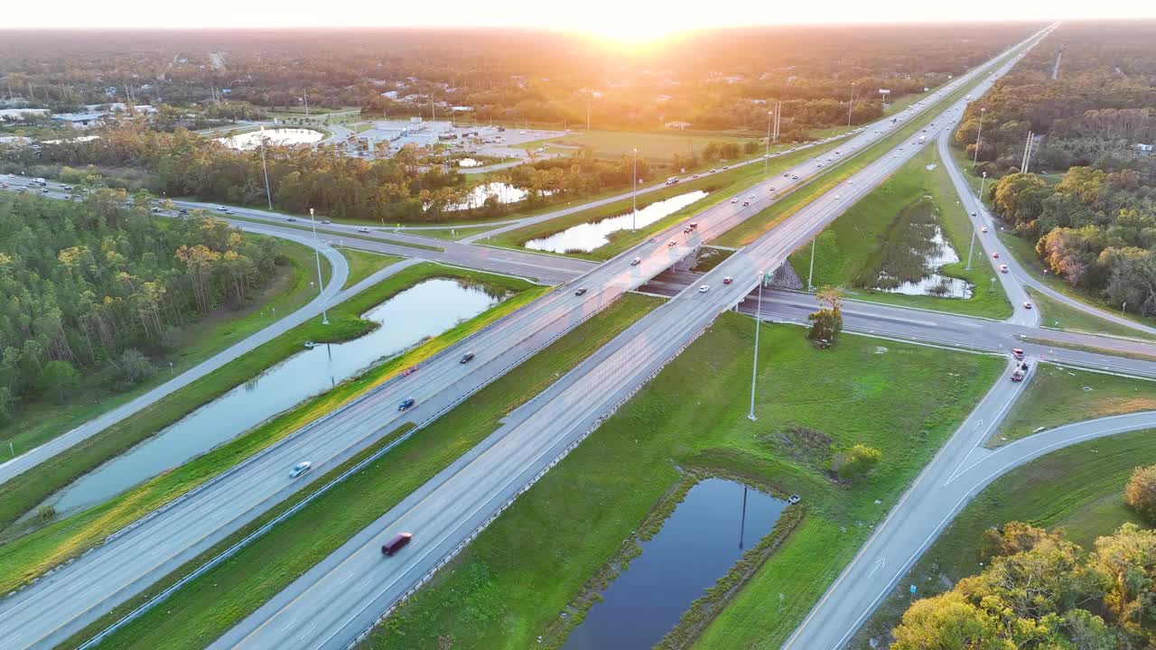 日出时高速公路出口交叉口的高架视图，车道上有快速移动的车辆和卡车。美国州际交通基础设施视频素材