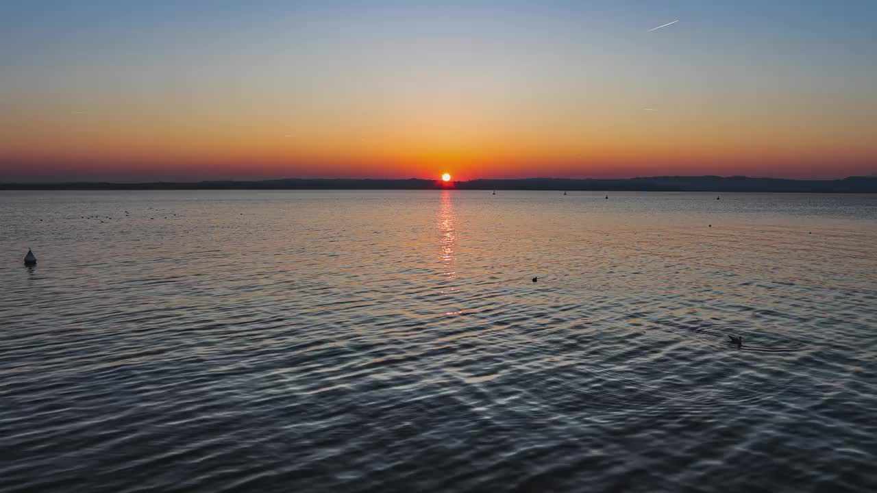 意大利加尔达湖上美丽的日落，太阳反射在平静的水面上视频素材