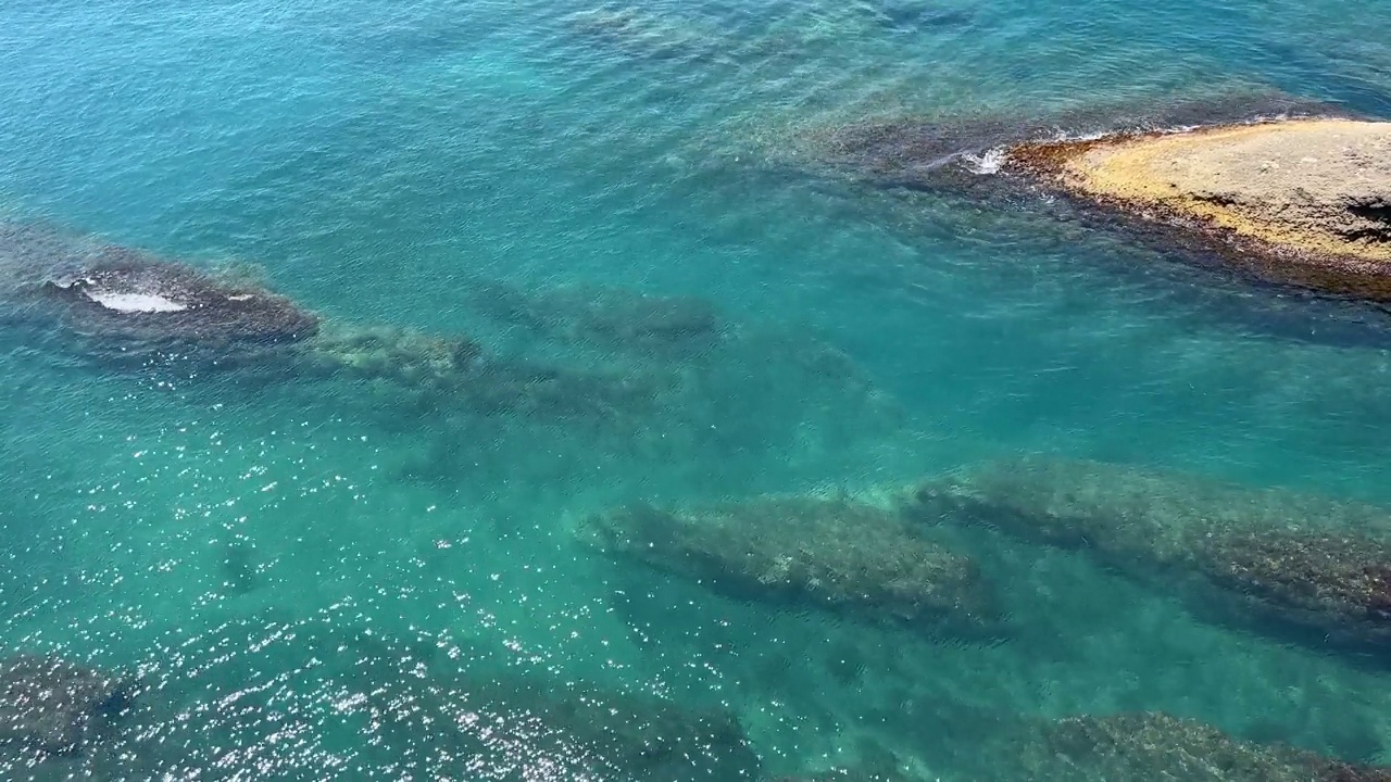 闪亮的蓝绿色海水的岩石海岸。视频素材