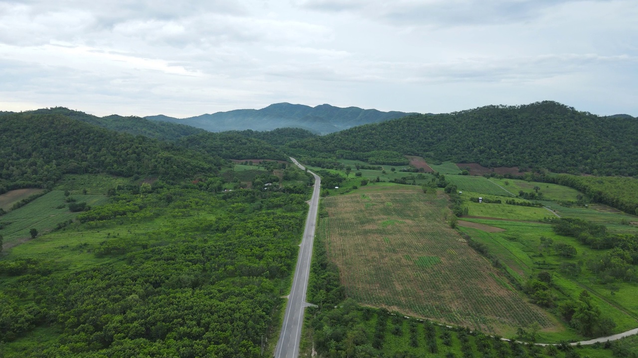 道路穿过郁郁葱葱的大自然，群山环绕着晴朗的天空。视频素材