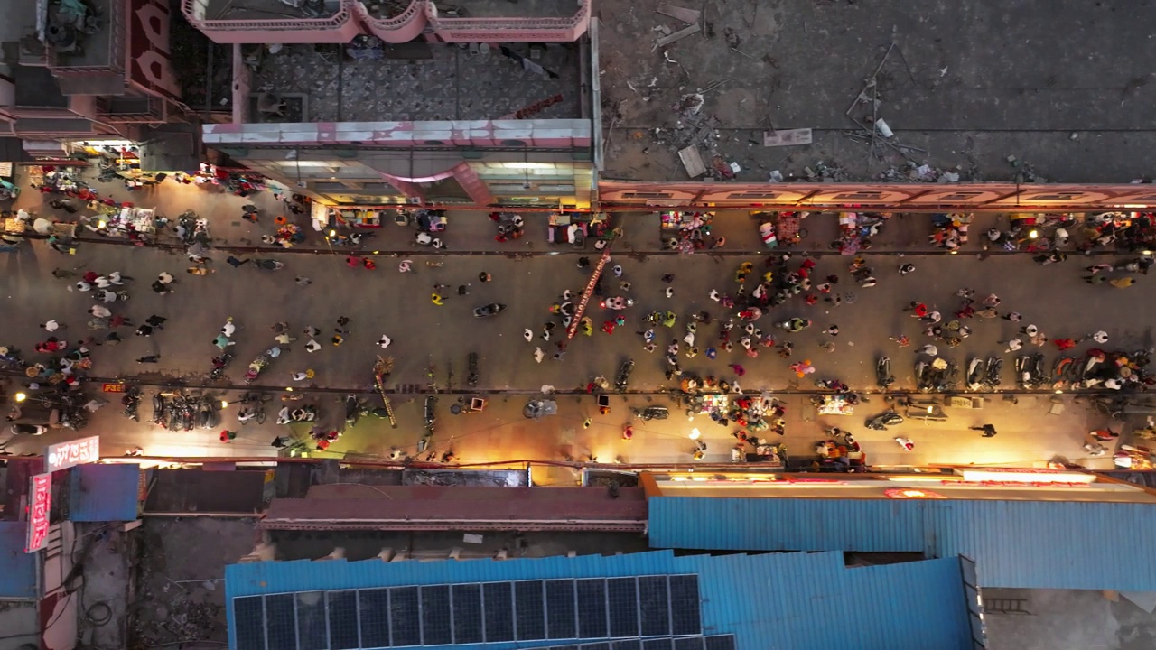 从空中俯瞰印度瓦拉纳西一个繁忙的夜市，小贩们在兜售商品，熙熙攘攘的人群在热闹的场景中穿行。视频下载