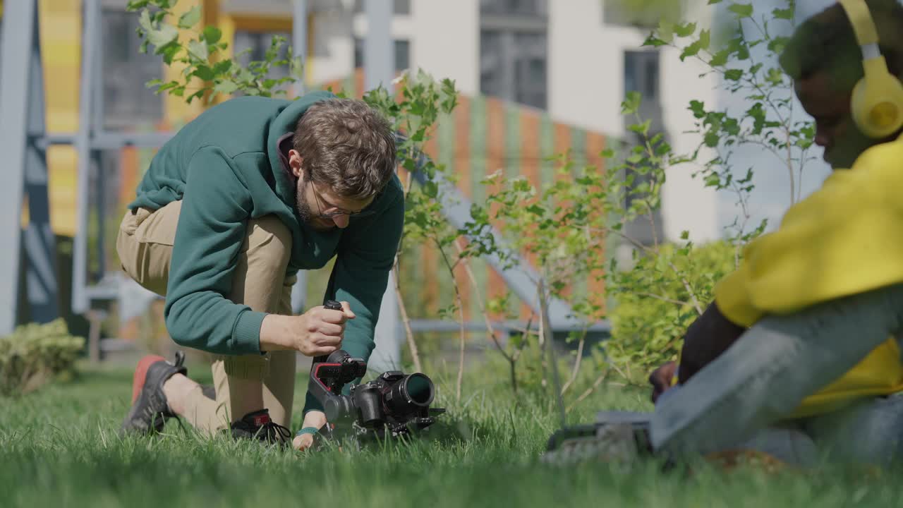 摄影师拍摄了一个坐在多层建筑草坪上的年轻黑人的特写镜头。后台。慢动作视频素材