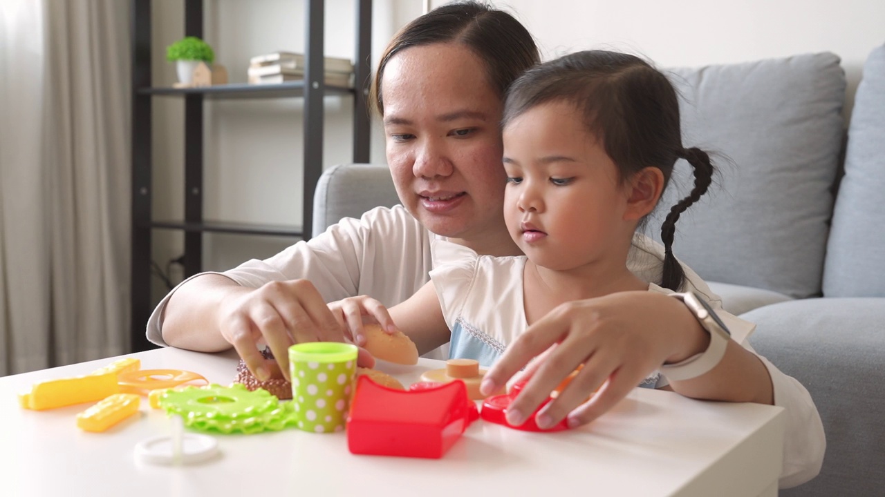 童年的快乐，妈妈和小女孩一起玩塑料儿童玩具视频素材