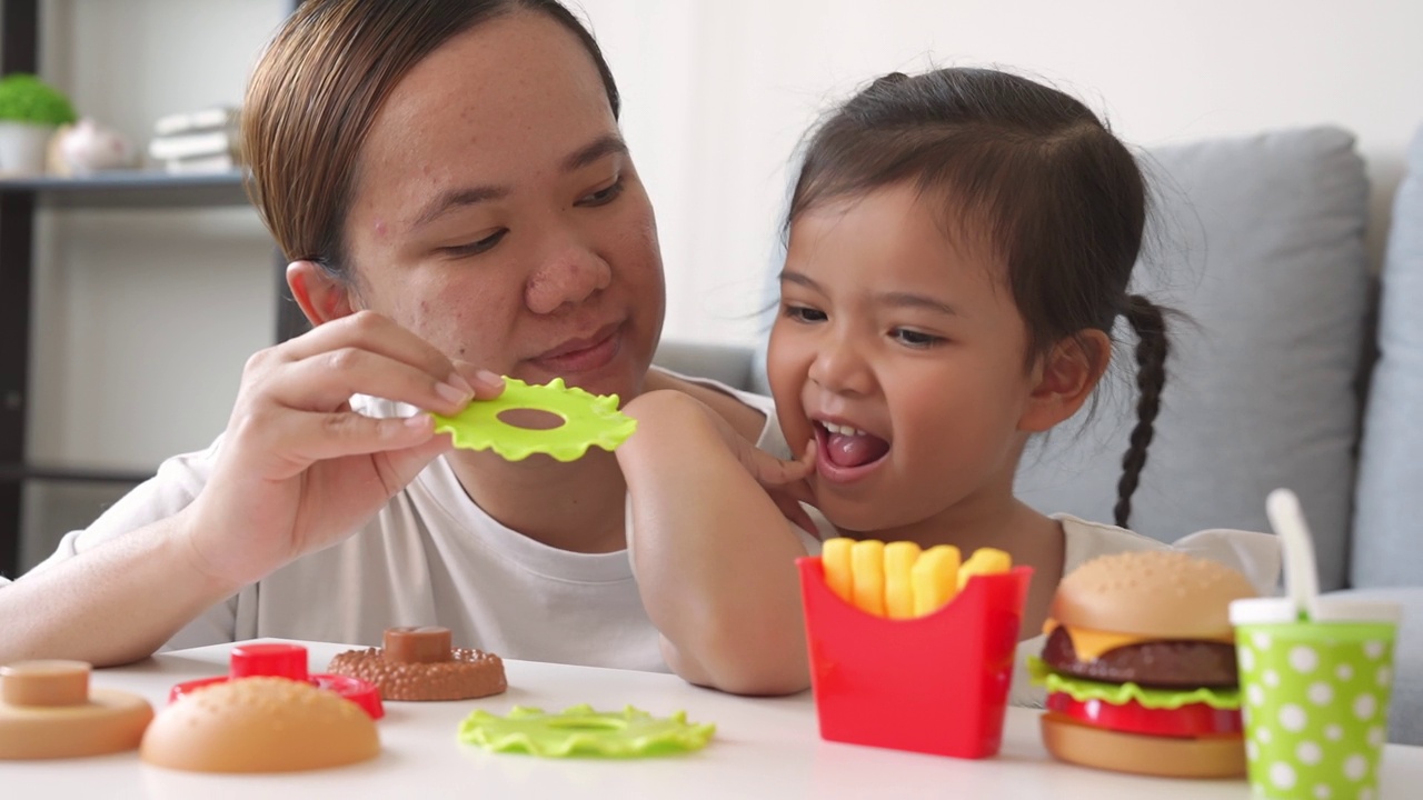 一个顽皮的亚洲妈妈和一个小女孩玩塑料儿童玩具视频素材