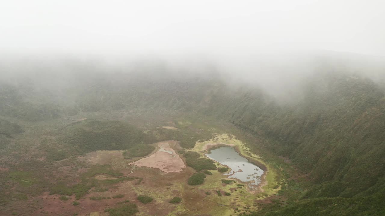 多雾的天气里，在绿色的森林山丘之间的山谷中，无人机俯瞰池塘视频素材