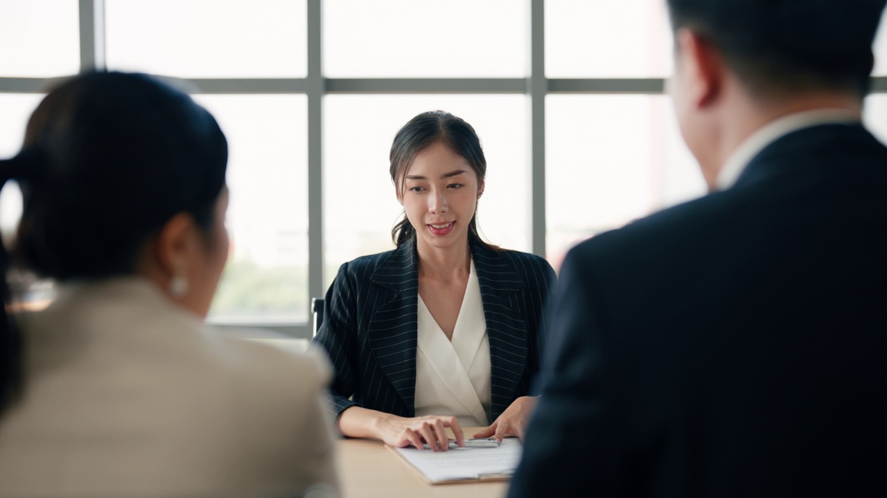 两名亚洲商人在面试结束后同意给一名女性候选人提供工作。视频素材