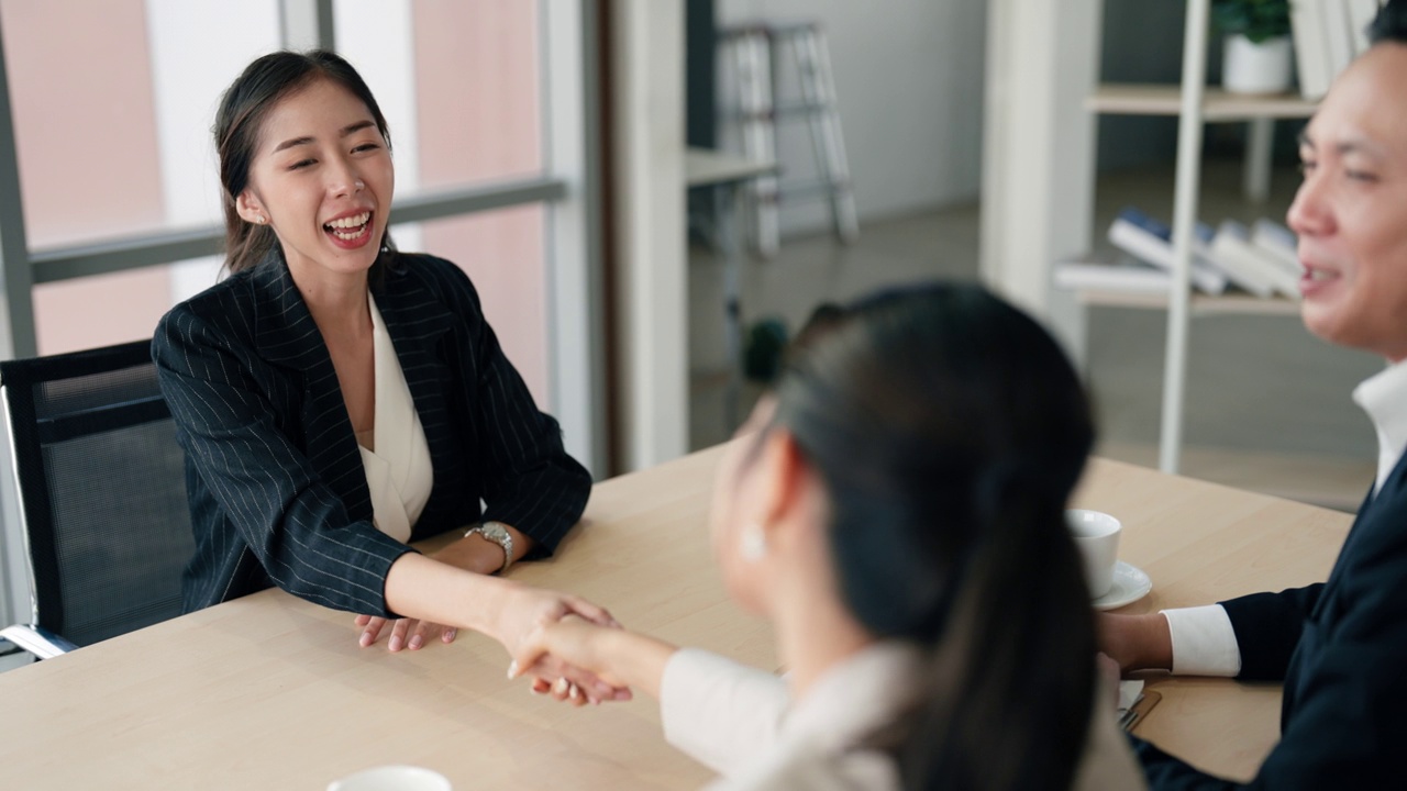 一位亚洲女性候选人在两名商人同意为她提供一份工作后，正在注册申请。视频素材