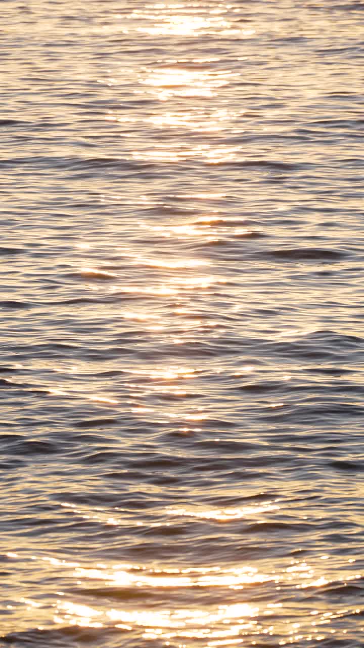 近距离观察海浪与日落背景下的太阳反射视频素材