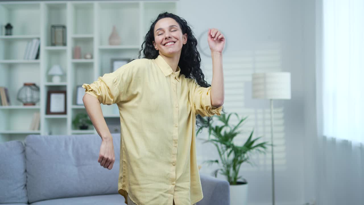 快乐快乐的年轻漂亮的女人在家里的客厅里跳舞。视频素材