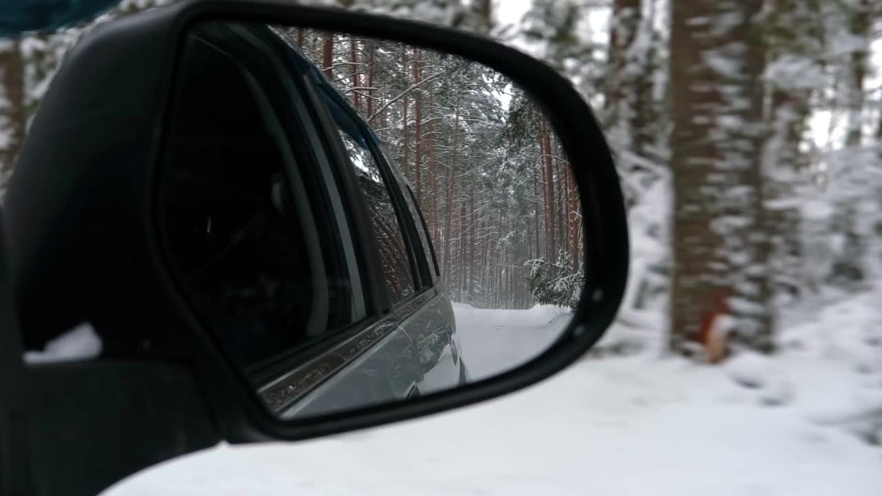 侧视镜反射的冬季森林道路。风景与空旷的高速公路穿过雪林。汽车在路上超速行驶。自动运动。旅游、旅行、旅行的概念。白雪覆盖着树木。视频素材