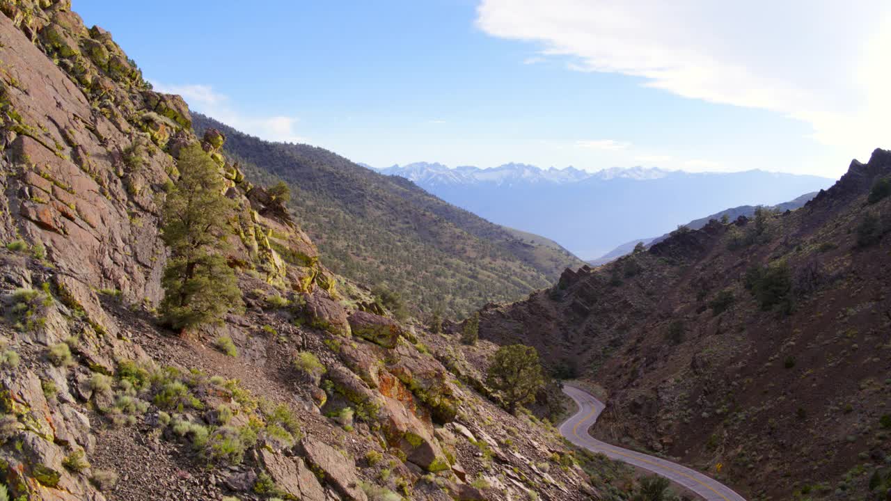 空中拍摄的蜿蜒的道路在山对天空，无人机在山谷上空向后飞行-猛犸湖，加利福尼亚视频素材