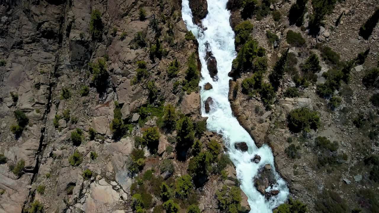 在阳光明媚的日子里，空中拍摄的瀑布在岩石中，无人机在山上的植物上向前上升-猛犸湖，加利福尼亚视频素材