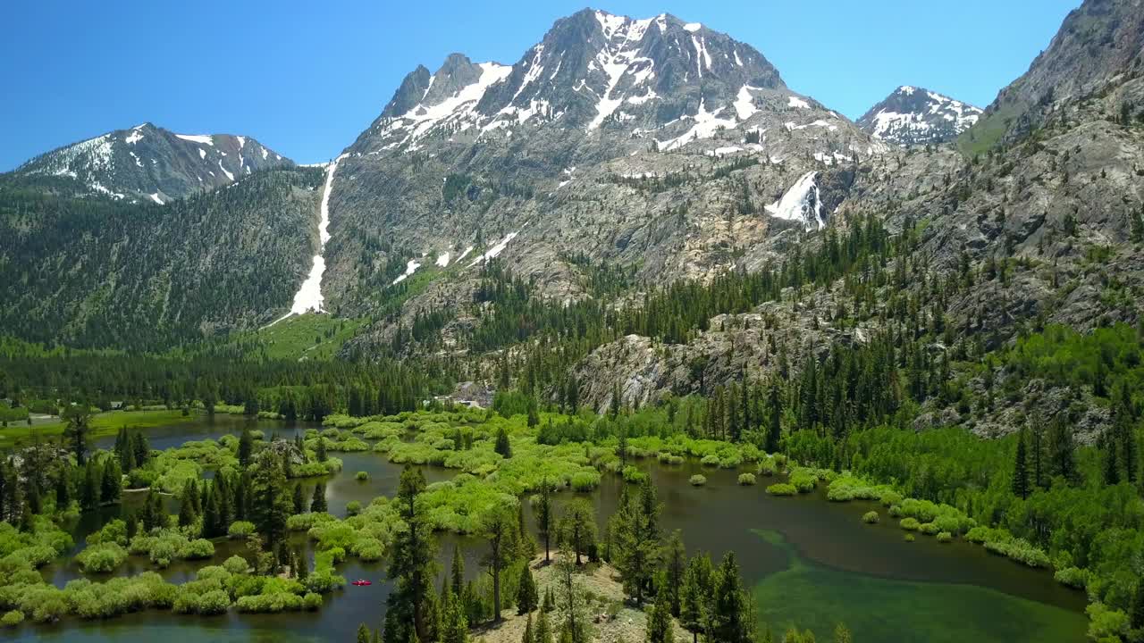 空中拍摄的湖泊在青山附近的树木，无人机向前飞行在自然景观对天空-猛犸湖，加利福尼亚视频素材