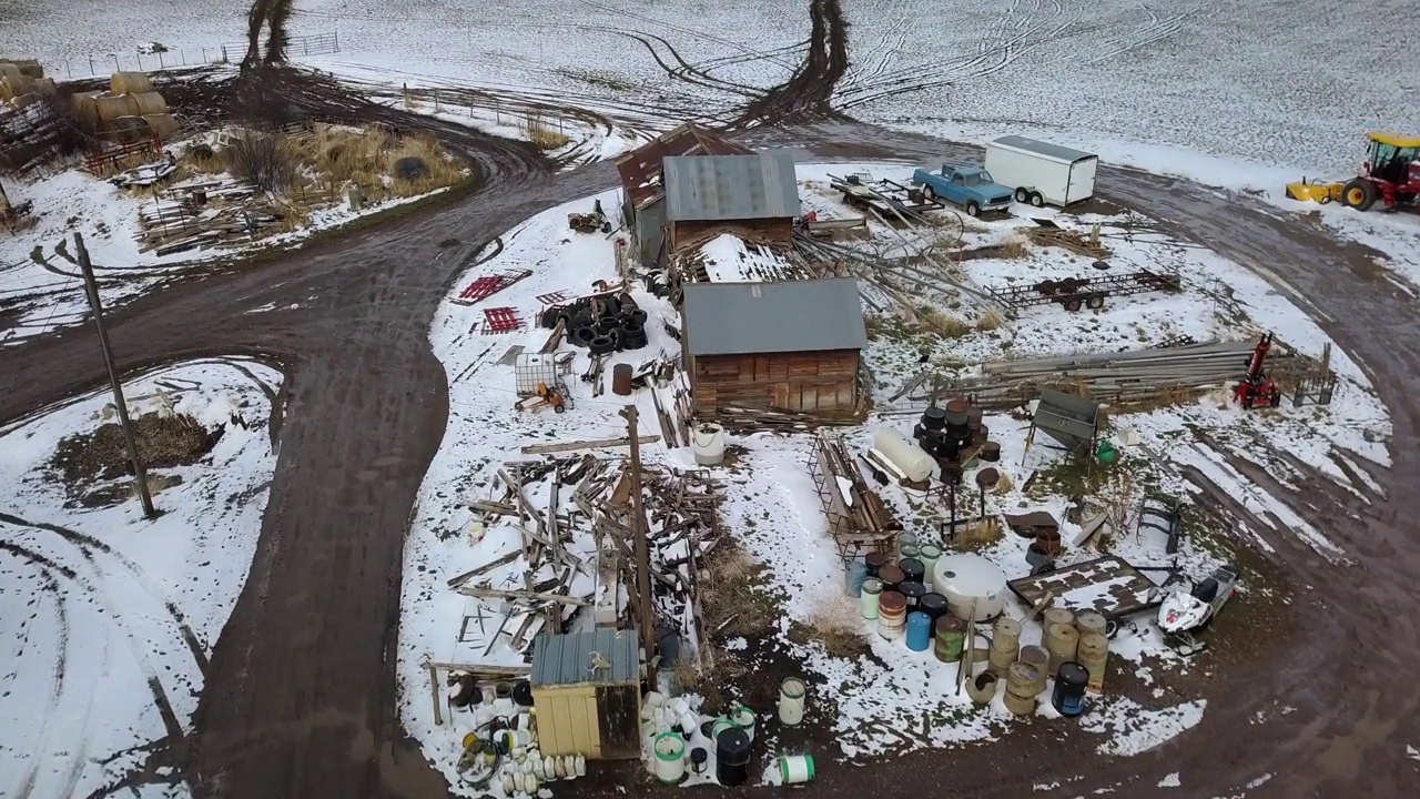 空中倾斜拍摄的建筑物在雪地上的道路，无人机向前飞行在景观对天空-比林斯，蒙大拿州视频素材