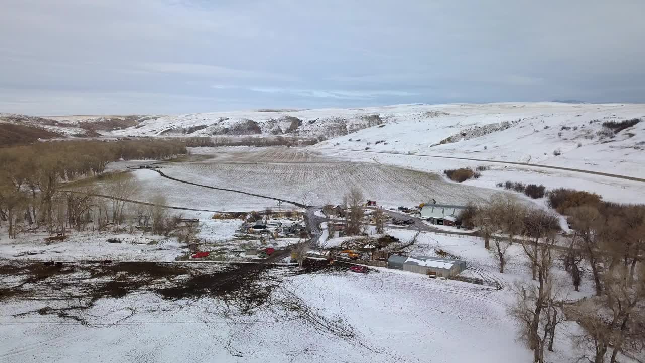 空中平移拍摄的结构和车辆裸露的树木对天空，无人机飞越雪景-比林斯，蒙大拿州视频素材