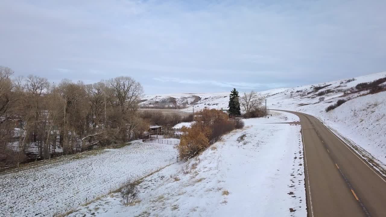 在蒙大拿州比林斯，空无一人的道路上的雪对着天空的建筑物，无人机向前飞行在景观视频素材