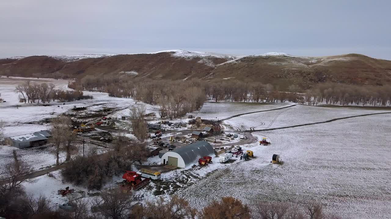 空中拍摄的建筑物和车辆附近光秃秃的树，无人机飞越雪景对天空-比林斯，蒙大拿州视频素材