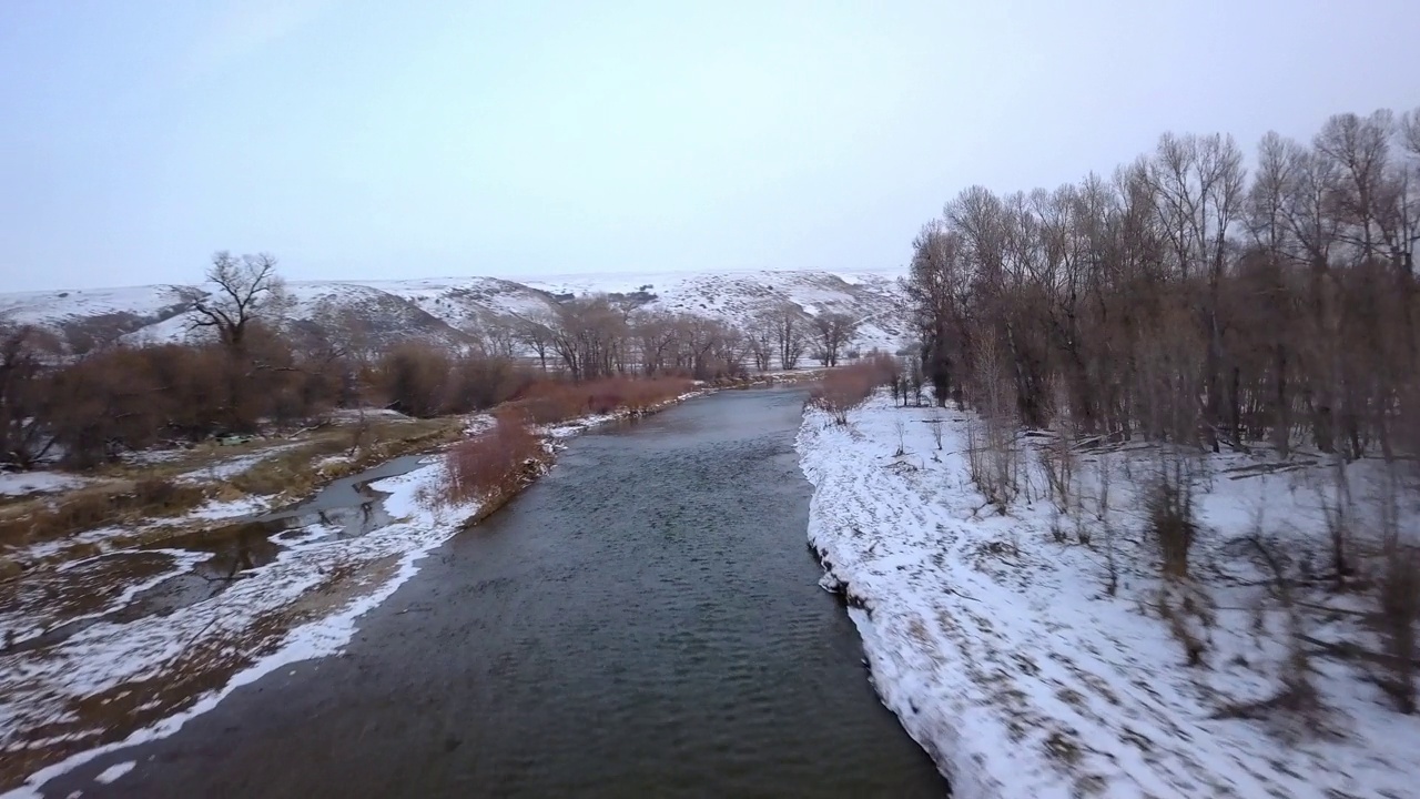 空中平移拍摄的河流在森林和山区的雪，无人机飞行在自然景观对天空-比林斯，蒙大拿州视频素材