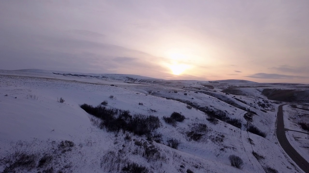 空中拍摄的雪山附近的道路对天空在日落，无人机飞越景观-比林斯，蒙大拿州视频素材