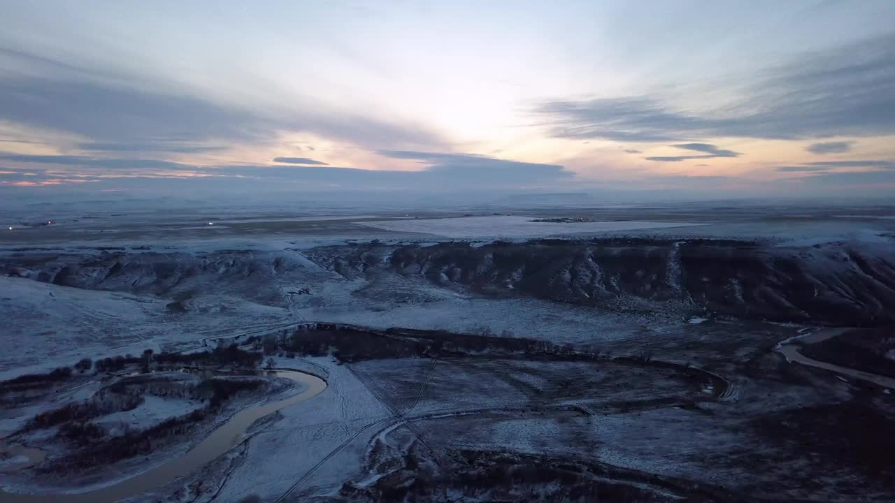 空中平移拍摄的河流和雪景对多云的天空在日落-比林斯，蒙大拿州视频素材