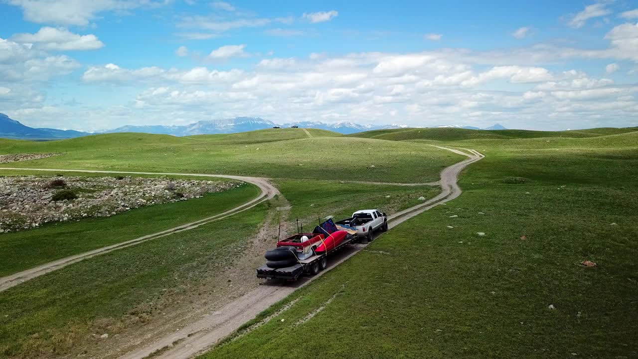 航拍:无人机飞越皮卡车与拖车在泥泞的道路上在青山对天空-比林斯，蒙大拿州视频素材