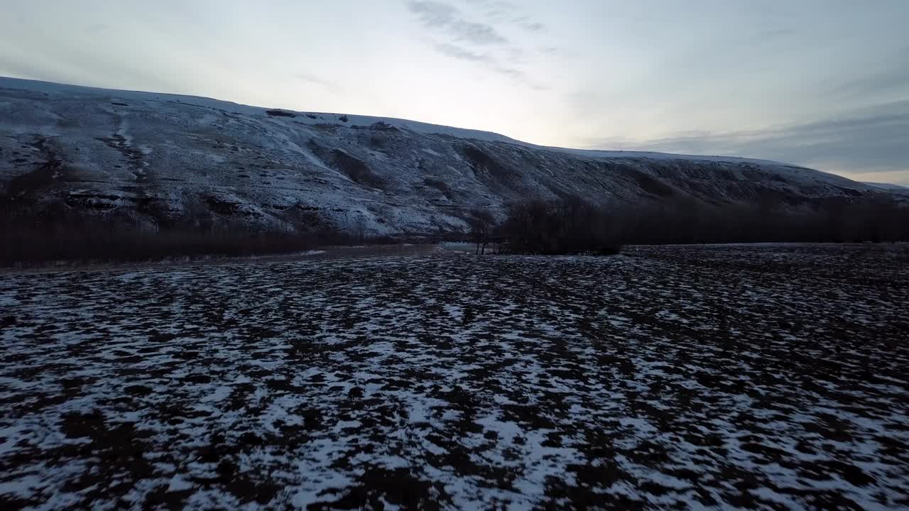 航拍:无人机在日落时飞过白雪皑皑的山脉附近的河流和天空，蒙大拿比林斯视频素材