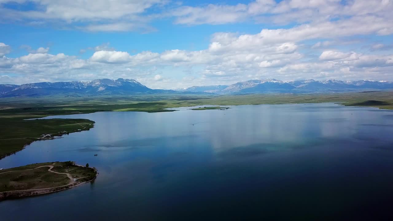 空中拍摄的船在湖附近的山脉对着天空，无人机在湖边的车辆上向后飞行-比林斯，蒙大拿州视频素材