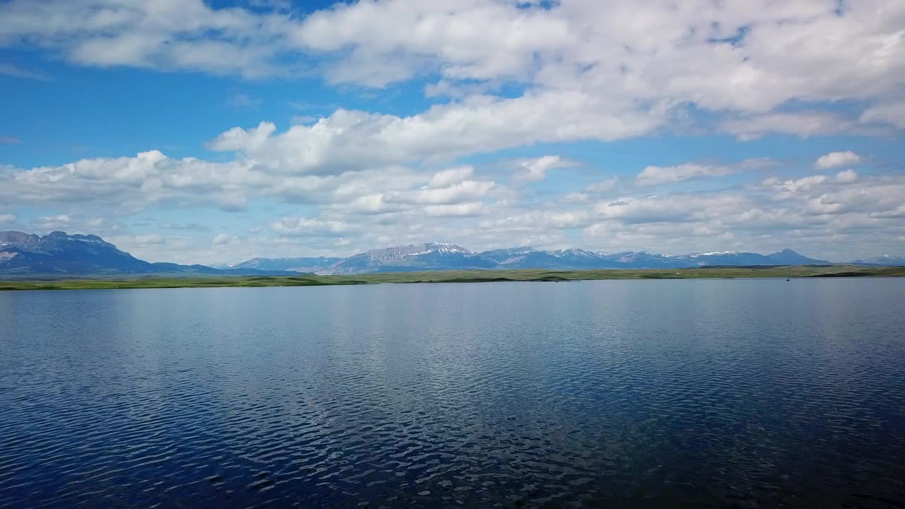 大篷车在山脉附近的湖泊航拍，无人机在自然景观上向后上升，对着天空——蒙大拿比林斯视频素材