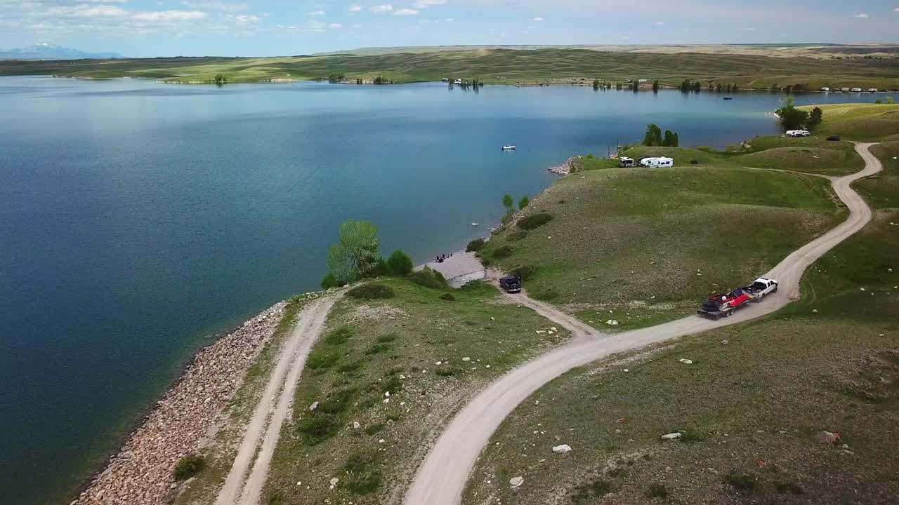 空中平移拍摄的皮卡车与拖车在湖边的道路上，无人机飞越湖对天空-比林斯，蒙大拿州视频素材