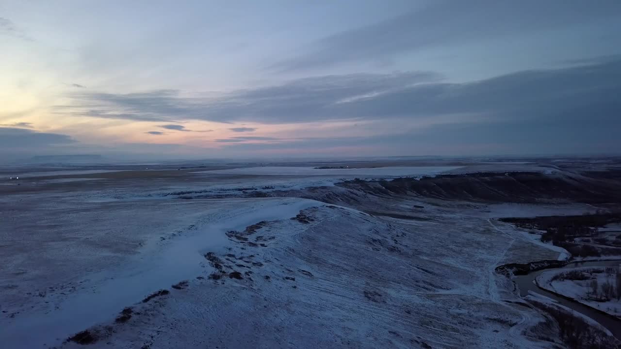 空中平移拍摄的雪景和河流对多云的天空在日落-比林斯，蒙大拿州视频素材