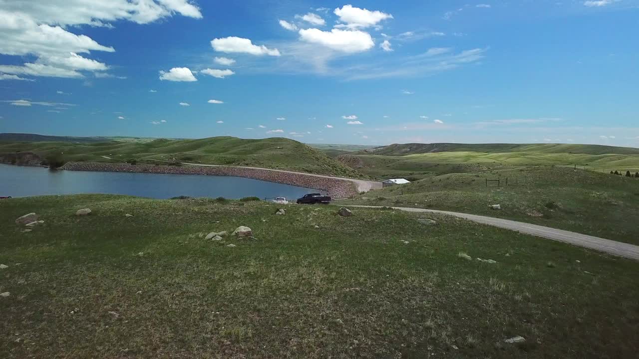 航拍:无人机在湖边的土路上飞过皮卡车，在阳光明媚的日子里，蓝天在蒙大拿州比林斯视频素材