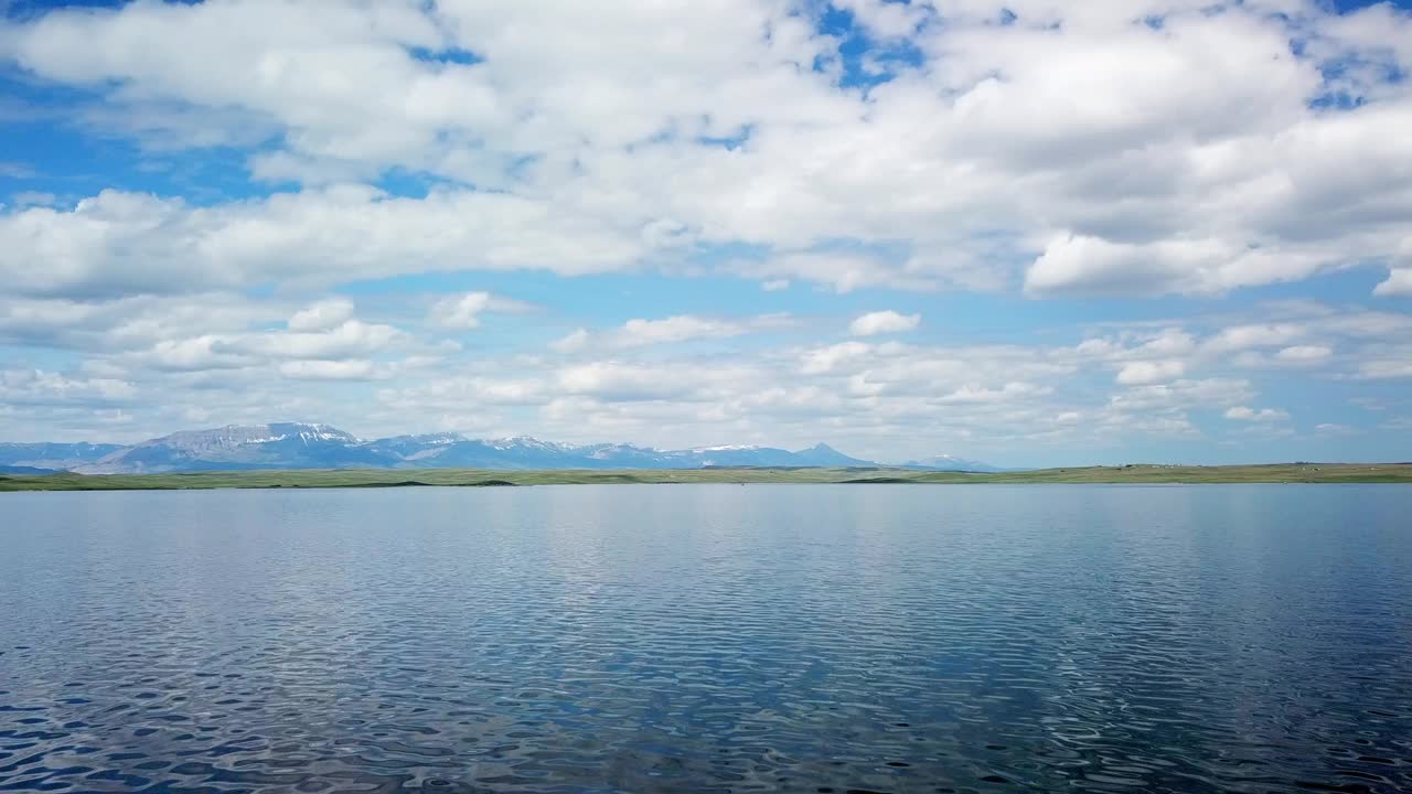 空中平移拍摄的湖泊附近的山脉对天空，无人机在水面上向前飞行-比林斯，蒙大拿州视频素材