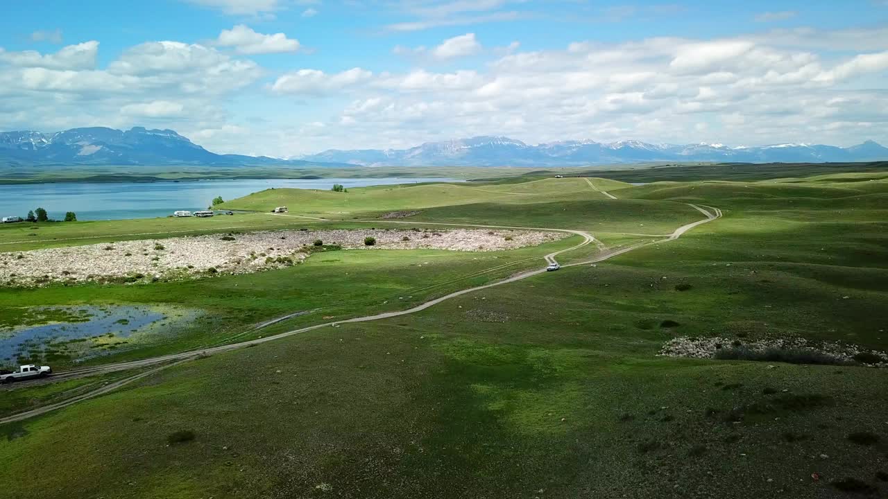 空中平移拍摄的皮卡车与拖车在湖边的道路上，无人机飞过绿色景观对天空-比林斯，蒙大拿州视频素材