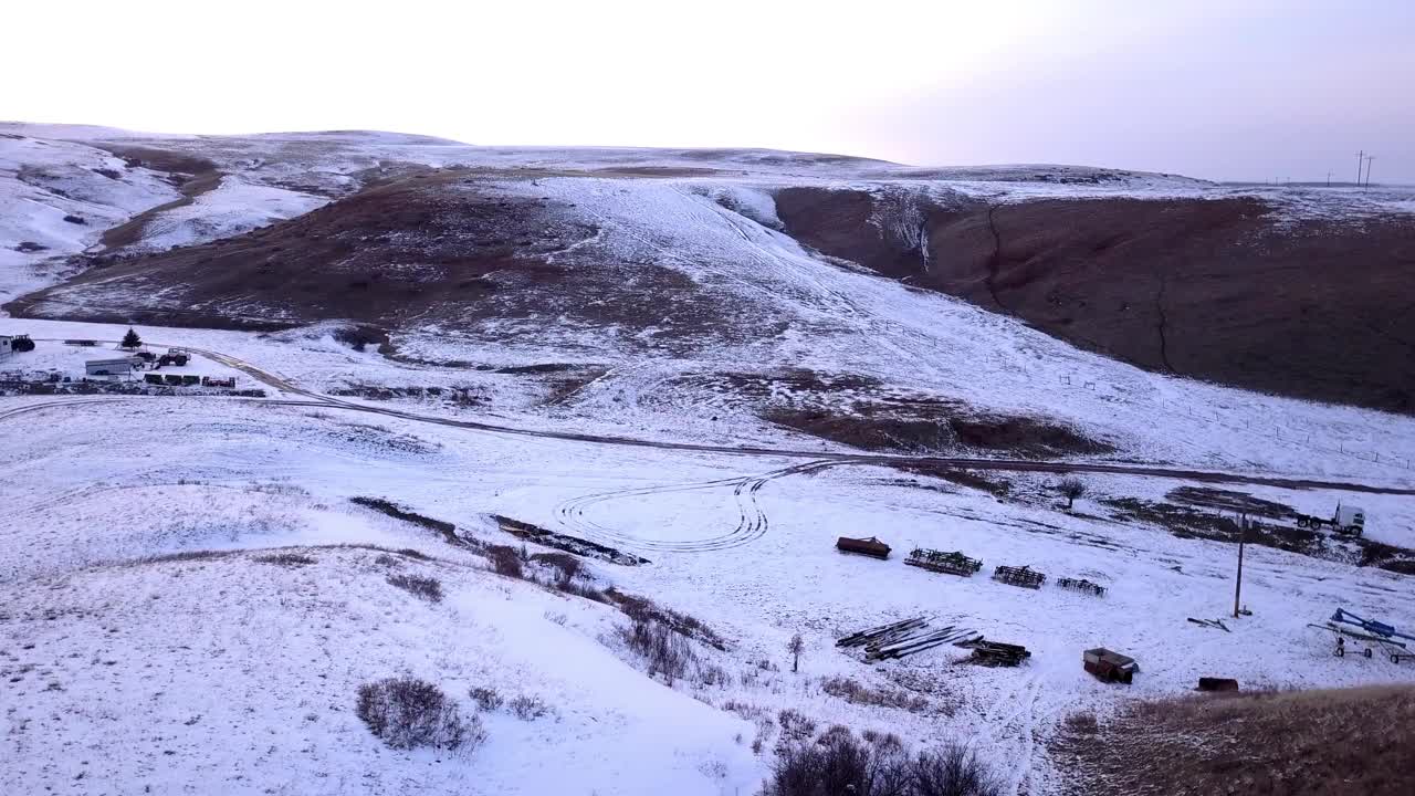 空中平移拍摄的白雪皑皑的山脉附近的结构对天空，无人机飞越景观在日落-比林斯，蒙大拿州视频素材