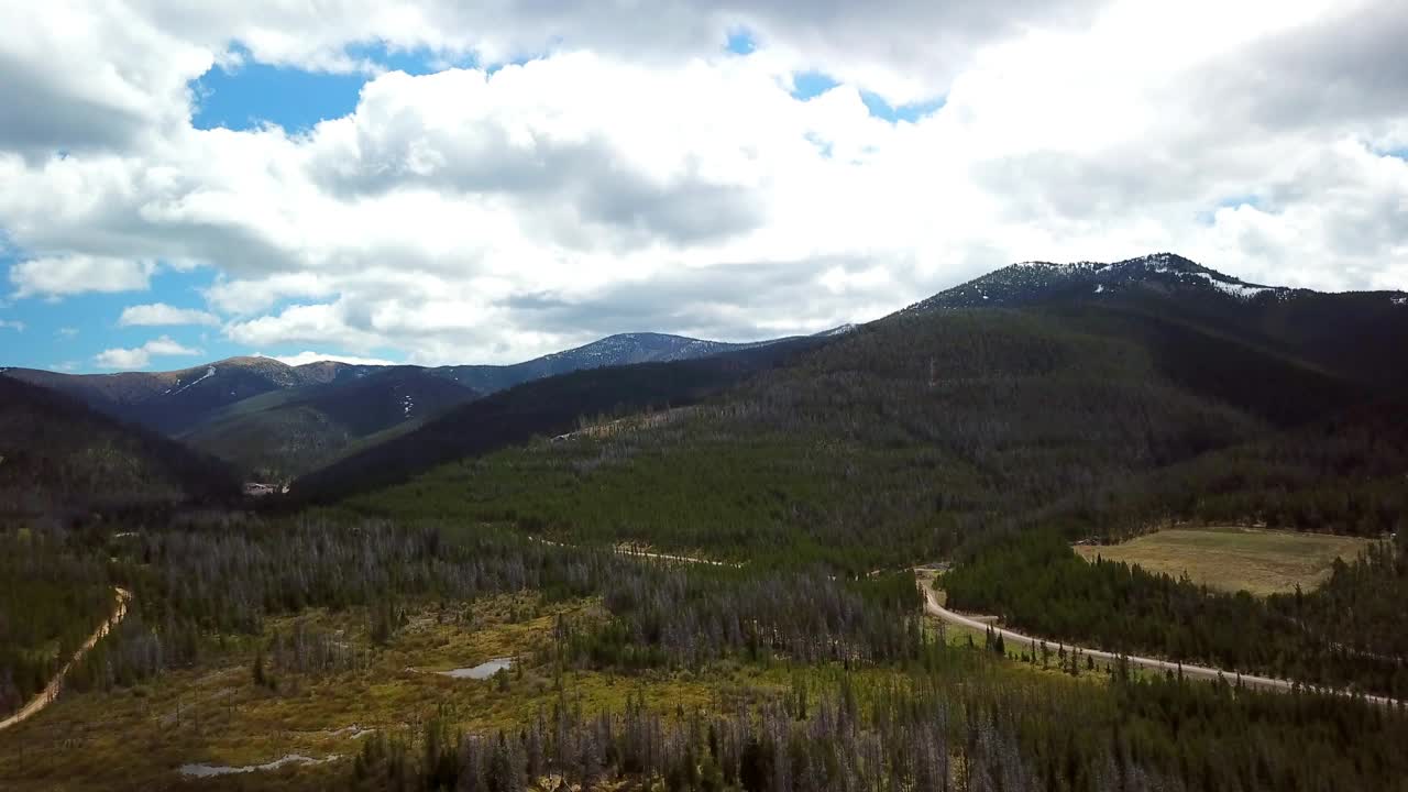 空中拍摄的绿色树木在森林和道路附近的山，无人机向前飞行在自然景观-比林斯，蒙大拿州视频素材