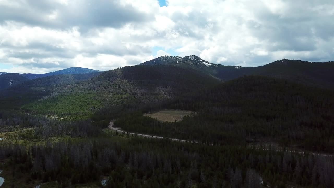 空中平移拍摄的道路在树木附近的山对天空，无人机飞越自然景观-比林斯，蒙大拿州视频素材