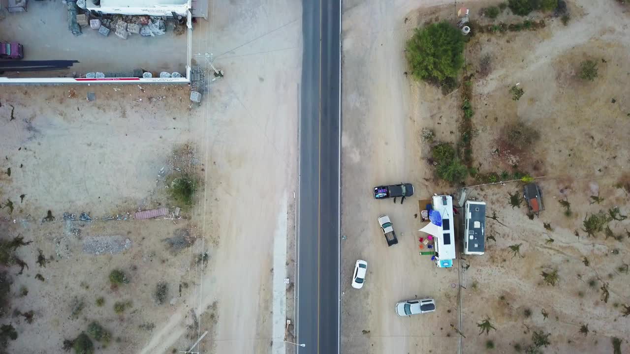 在建筑物和工厂之间的道路上的车辆的鸟瞰图，无人机在汽车上向前飞行-下加利福尼亚州，墨西哥视频素材