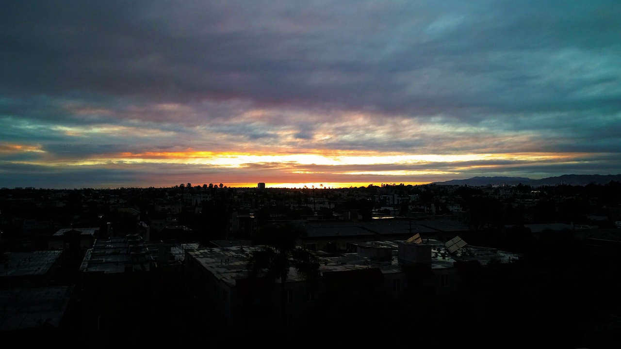 夕阳下多云的天空下，城市建筑物的航拍，无人机在城市景观上向前飞行-卡尔弗城，加利福尼亚视频素材